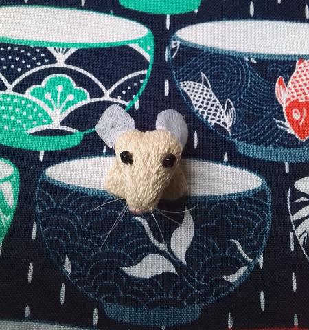 A 3D mouse peers out from a cup