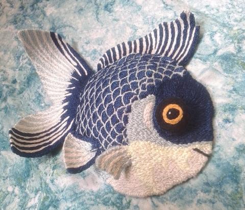A large blue fish, with dark scales, bulgy yellow and black eye and blue and white fins