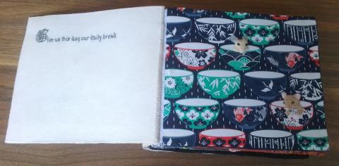 On the left is the text, in black thread on a white background. On the right are five rows of teacups, two of which have mice sitting in them.