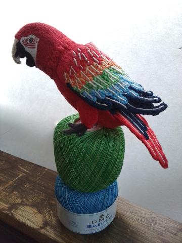 The parrot sits on some of the variegated Babylo crochet thread (green and blue) which was used for its wings. The texture of the embroidery on the feathers is more visible in this photo.